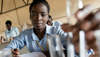 An adolescent girl conducts an experiment during a chemistry class in Kamulanga Secondary School in Lusaka, Zambia.