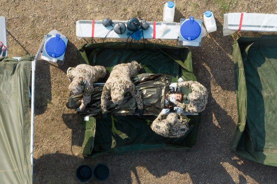 Overhead shot of soldiers in protective gear working on a mannequin
