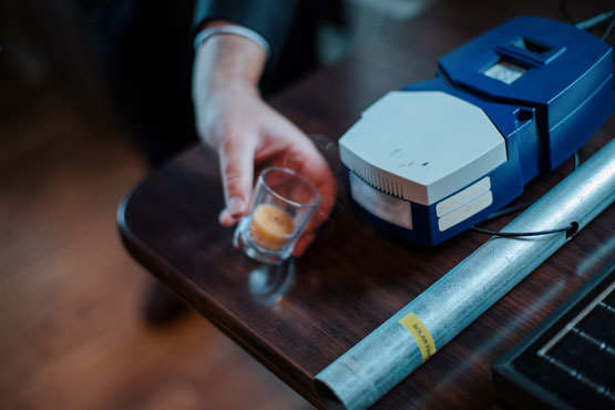 A person holds a candle wafting smoke near a sensor and an antenna on a table.